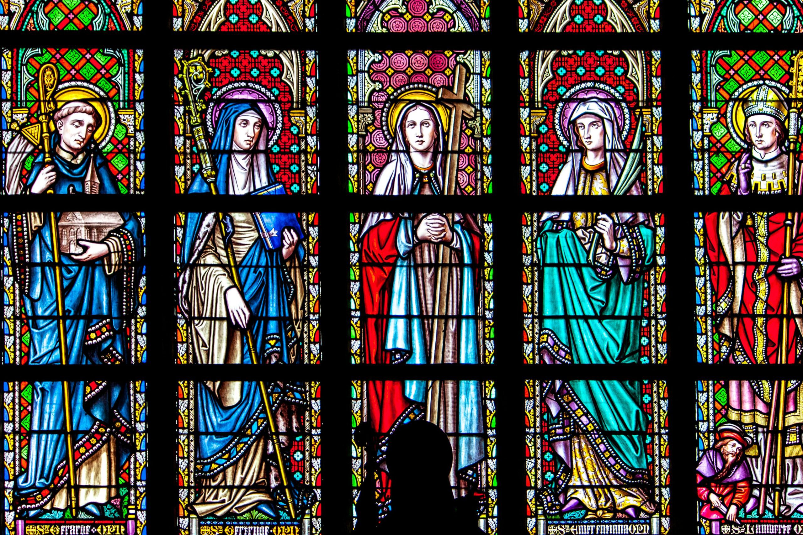 Intricate stained glass panel depicting saints in a historic church setting.